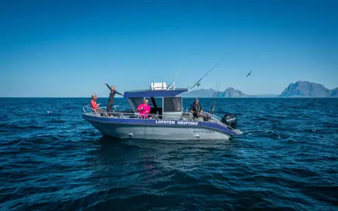 Fisketur i Nordnorge med båten "Lofoten Havfiske". Soligt och blåsigt, med berg i bakgrunden.