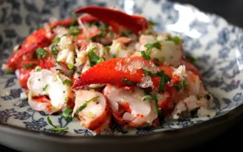 Homard frais servi avec des perles de citron caviar, une recette raffinée pour un plat d'exception.