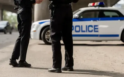 Dwóch policjantów stoi obok radiowozu.