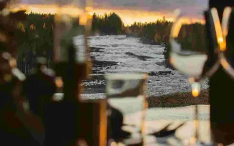 Storforsen camping: en brusande fors i solnedgången, med skog och träd som ramar in. Mysig belysning i förgrunden.