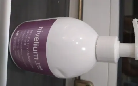 Biała butelka z pompką, na której widnieje napis "nivelium med krem dermatologiczny emolient". Idealny dla skóry z AZS i łuszczycą.