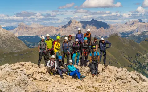 Grupa turystów w sprzęcie wspinaczkowym pozuje na tle górskich krajobrazów Dolomitów. To wspaniała przygoda na via ferrata Dolomity!
