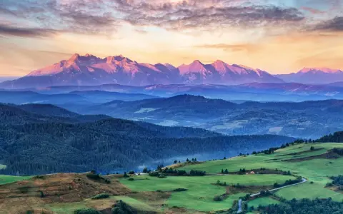 Tatry o zachodzie słońca, jedno z **10 najpiękniejszych miejsc w Polsce**. Góry w odcieniach różu i fioletu, zielone wzgórza i lasy.