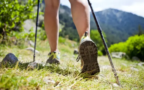Nauka jak chodzić z kijkami to klucz do stabilności na górskim szlaku. Widok na nogi w butach trekkingowych i kijki wspierające marsz.