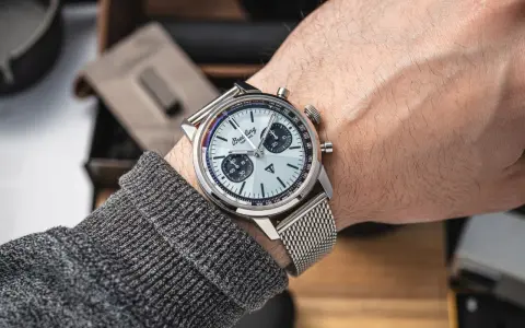 Mężczyzna prezentuje swój lśniący zegarek Breitling, gotowy do czyszczenia. Metalowa bransoleta i tarcza z chronografem błyszczą.