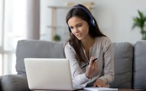Kobieta w słuchawkach pracuje przy laptopie, tworząc komfortowy **home office**.