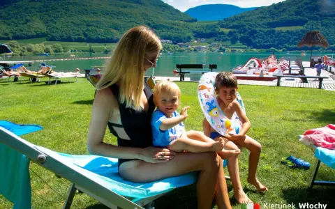 Rodzina odpoczywa nad jeziorem Lago di Caldaro. Słońce, zieleń i woda tworzą idealne wakacje.