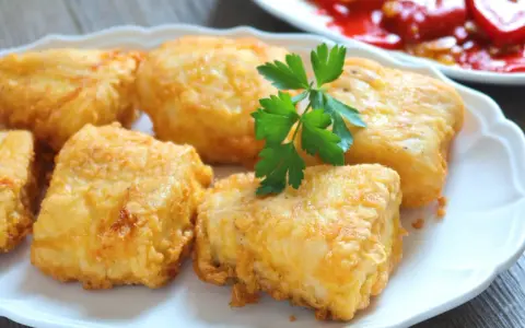 Crujientes trozos de merluza a la romana, dorados y listos para disfrutar. Un clásico plato español.