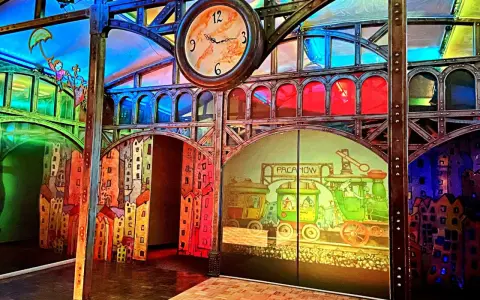 Kolorowa sceneria z pociągami i bajkowymi postaciami, idealna na pacanów atrakcje dla dzieci. Zegar nadaje miejscu magiczny klimat.
