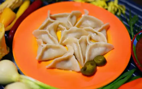 Pyszne pierogi meksykańskie, ułożone na pomarańczowym talerzu, z dodatkiem jalapeño i sosu.