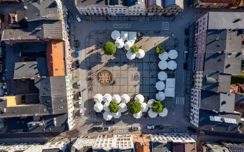 Widok z lotu ptaka na rynek w Kościerzynie, z białymi parasolami i zielenią.