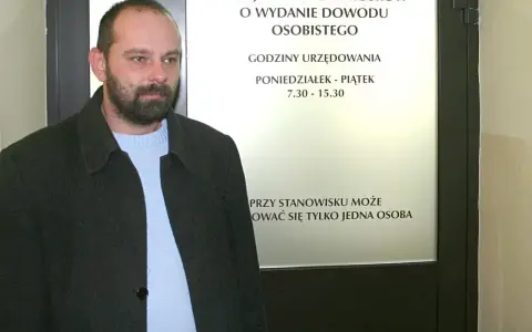 Mężczyzna z brodą przed urzędem, gdzie można złożyć wniosek o dowód. Sprawdź, ile kosztuje wyrobienie dowodu i godziny otwarcia.
