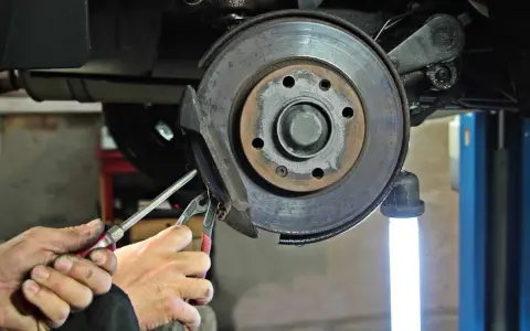 Mechaniker führt eine Inspektion am Bremssattel eines Mercedes durch. Der Service A steht an.