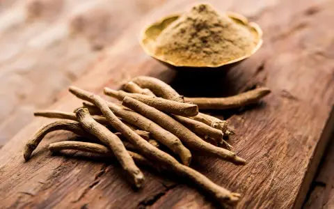Ashwagandha-Wurzeln und Pulver auf Holz. Die Frage "wie schnell wirkt Ashwagandha" beschäftigt viele, die auf natürliche Unterstützung setzen.