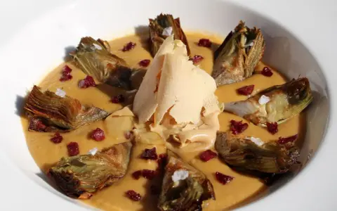 Delicioso guiso de alcachofas con trocitos de jamón y una lámina crujiente de queso.