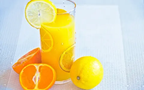 Succo d'arancia e limone, ricchi di vitamina C, in un bicchiere con fette di agrumi.