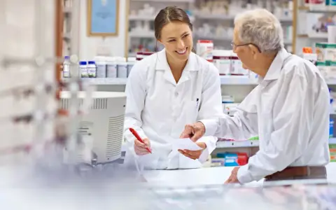 Farmaceutka wyjaśnia seniorowi, od kiedy dostępne są darmowe leki dla seniorów.