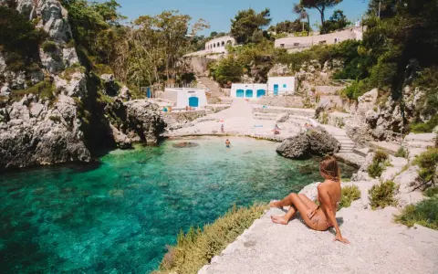 Una donna ammira il mare cristallino di una caletta pugliese. Perfetto per capire quando andare in Puglia per una vacanza indimenticabile.