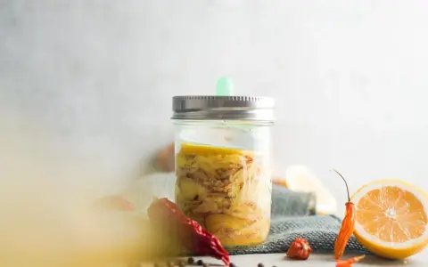 Ein Glas mit Ingwer fermentieren, daneben Zitronenscheiben und Chilis.