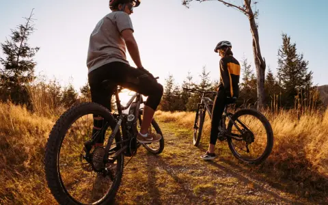 Dwie osoby na rowerach górskich odpoczywają na ścieżce wśród traw. Odkrywają malownicze trasy rowerowe Śląsk.