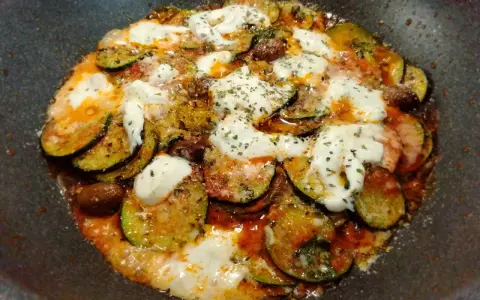 Zucchine alla pizzaiola in padella, con pomodoro, mozzarella filante e olive. Un piatto saporito e facile da preparare.