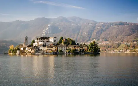 Isola di San Giulio, uno dei più bei posti da visitare in Piemonte, con il suo borgo antico sul lago d'Orta e le montagne sullo sfondo.