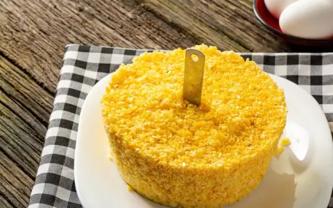 Un pastel de maíz amarillo con un cuchillo insertado, listo para servir. Una guía visual para como hacer cous cous.