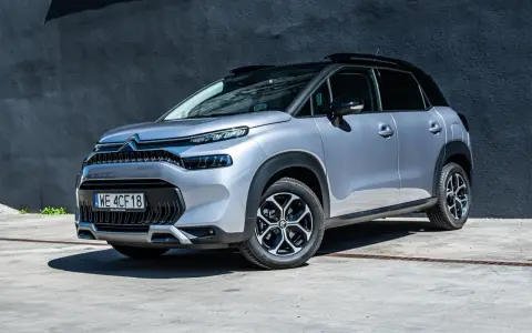 Srebrny Citroen C3 Aircross na tle ciemnej ściany. Wiele osób szuka **Citroen C3 Aircross opinie** przed zakupem.
