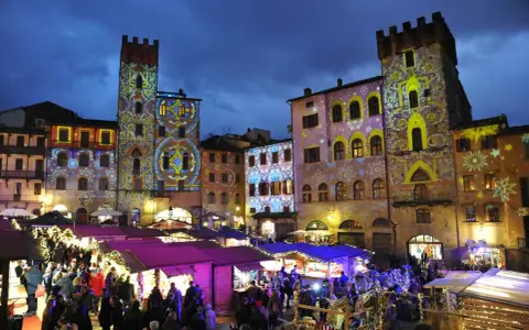 Un magico Arezzo tour: mercatini natalizi illuminati da proiezioni artistiche su torri e palazzi storici.