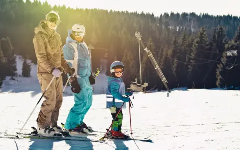 Rodzina na stoku narciarskim, idealnym dla dzieci. Słońce, śnieg i radość z jazdy.