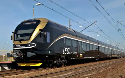 Nowoczesny, czarny pociąg LEO Express ze złotymi akcentami na torach.