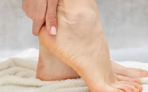 Main d'une personne massant son talon pour hydrater ses pieds.