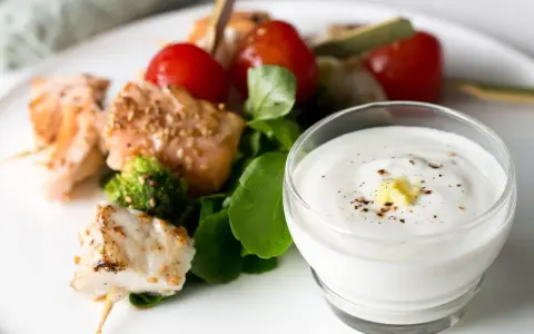 Brochettes de poisson et saumon grillés avec tomates cerises, brocolis et une sauce au yaourt crémeuse.