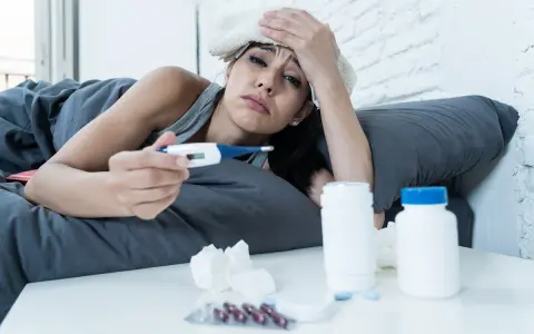 Donna malata a letto con termometro e medicine, preoccupata per i ciproxin effetti collaterali.