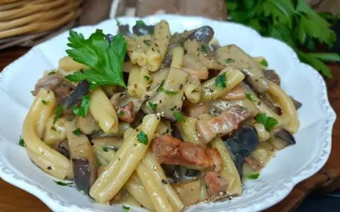 Un piatto invitante di pasta alla boscaiola con funghi e pancetta, guarnito con prezzemolo fresco.