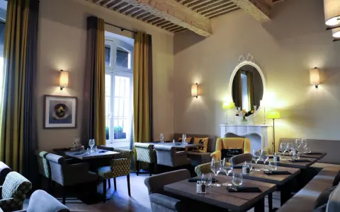 Salle à manger élégante avec tables dressées, fauteuils confortables et un miroir orné. L'ambiance évoque une **spécialité provençale** raffinée.