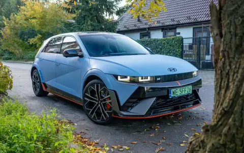 Niebieski Hyundai Ioniq 5 N z czerwonymi akcentami stoi na tle domu i drzew.