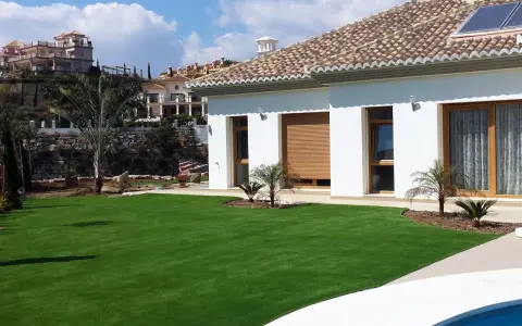 Modern villa con césped artificial en terrazas. Ideas para jardines de bajo mantenimiento y aspecto impecable.
