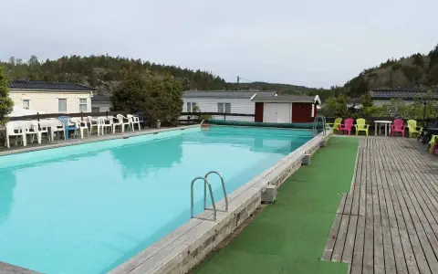 En stor pool med turkost vatten och solstolar i färgglada nyanser. En perfekt plats för avkoppling på camping Orust.