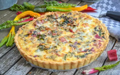Herzhafte Quiche mit buntem Mangold und knusprigem quiche teig auf Holztisch, garniert mit frischem Mangold.