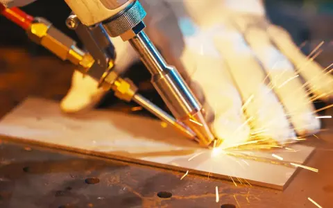 Precyzyjne spawanie laserowe aluminium, iskry sypią się podczas pracy.