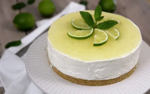 Cheesecake al mojito fresca e profumata, decorata con fettine di lime e menta.