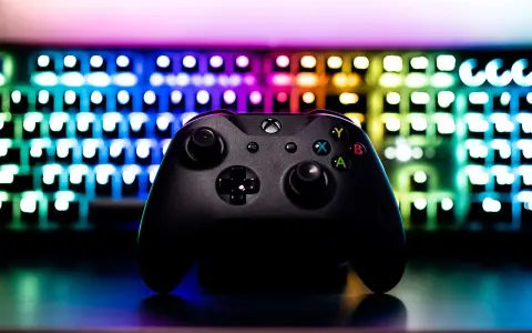 Czarny kontroler Xbox na tle podświetlanej klawiatury RGB. Idealny sprzęt do **grania na długie godziny**.
