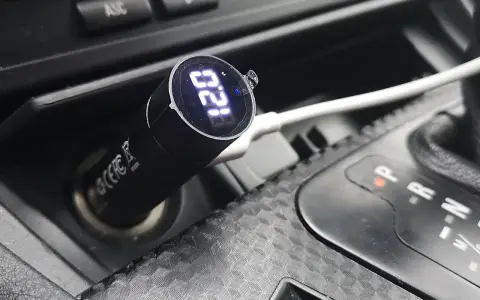 Nowoczesna zapalniczka w aucie z cyfrowym wyświetlaczem pokazuje 12.0V.