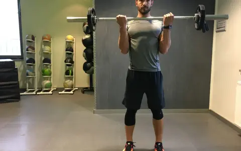 Mann macht Langhantel Curls im Fitnessstudio. Er trainiert seine Bizeps.