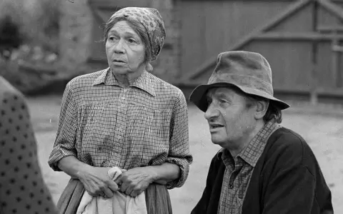 Marta Ławińska w stroju ludowym, obok mężczyzny w kapeluszu, w scenerii wiejskiej.