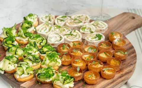 En härlig bricka med veganska snittar: rullade tortillawraps med krämig fyllning och gurka, samt små krispiga tarteletter med ost och marmelad.
