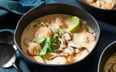 En skål med krämig tom kha gai med räkor, svamp och lime. En smakrik thailändsk soppa.