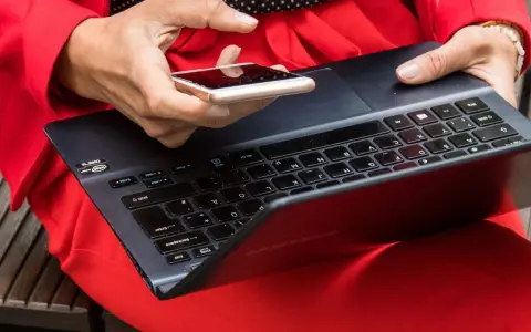 Besorgte Person prüft ihr Smartphone, nachdem ihr t-online Mail gehackt wurde. Sie hält es über eine Tastatur.
