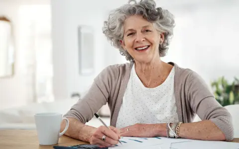 Mujer mayor sonríe mientras revisa un plan de pensiones, un ejemplo de reducción 40 para un rescate.